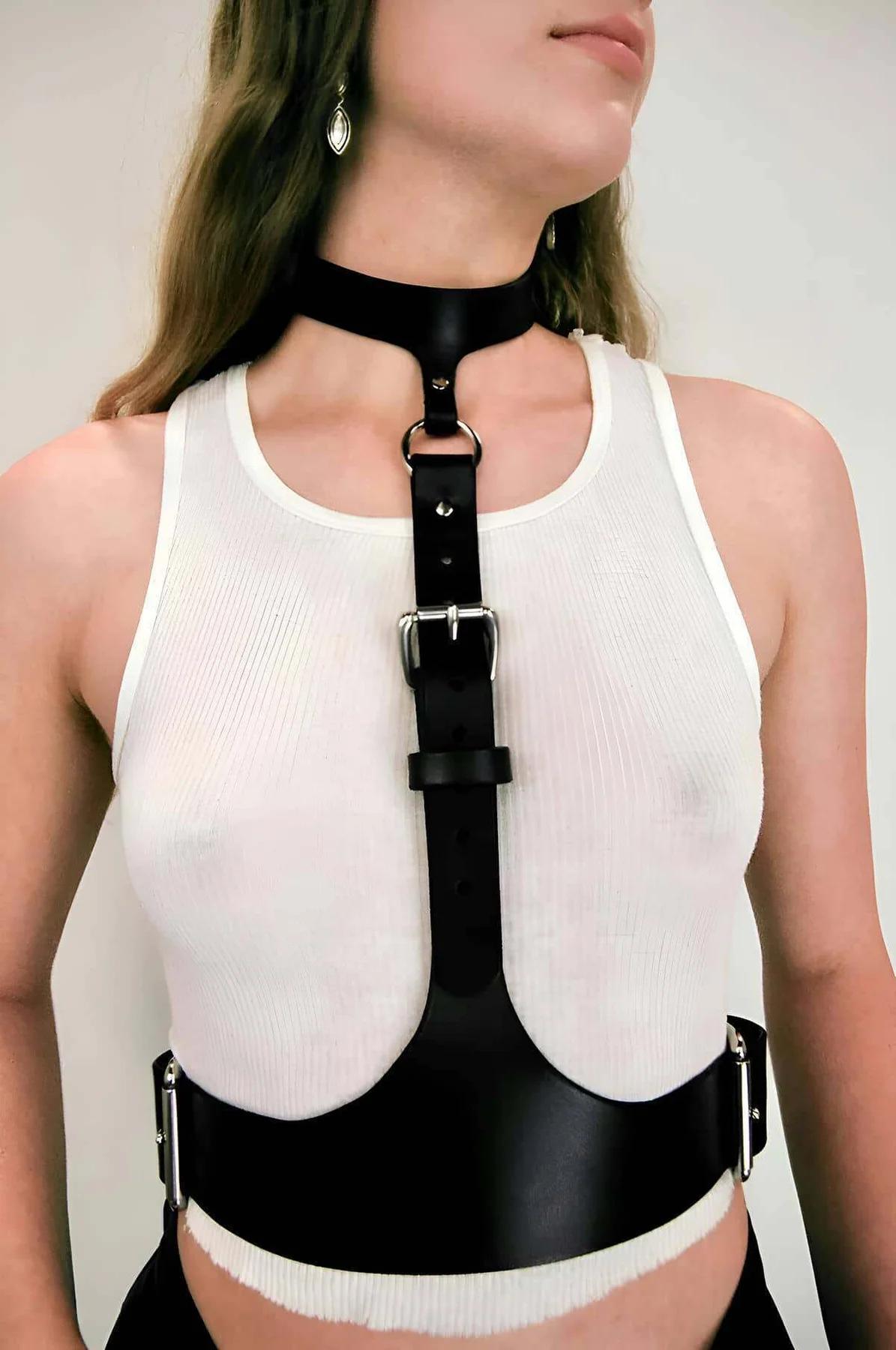 Black faux leather body harness with silver rectangular buckle, wide waist band, and integrated choker strap worn over white