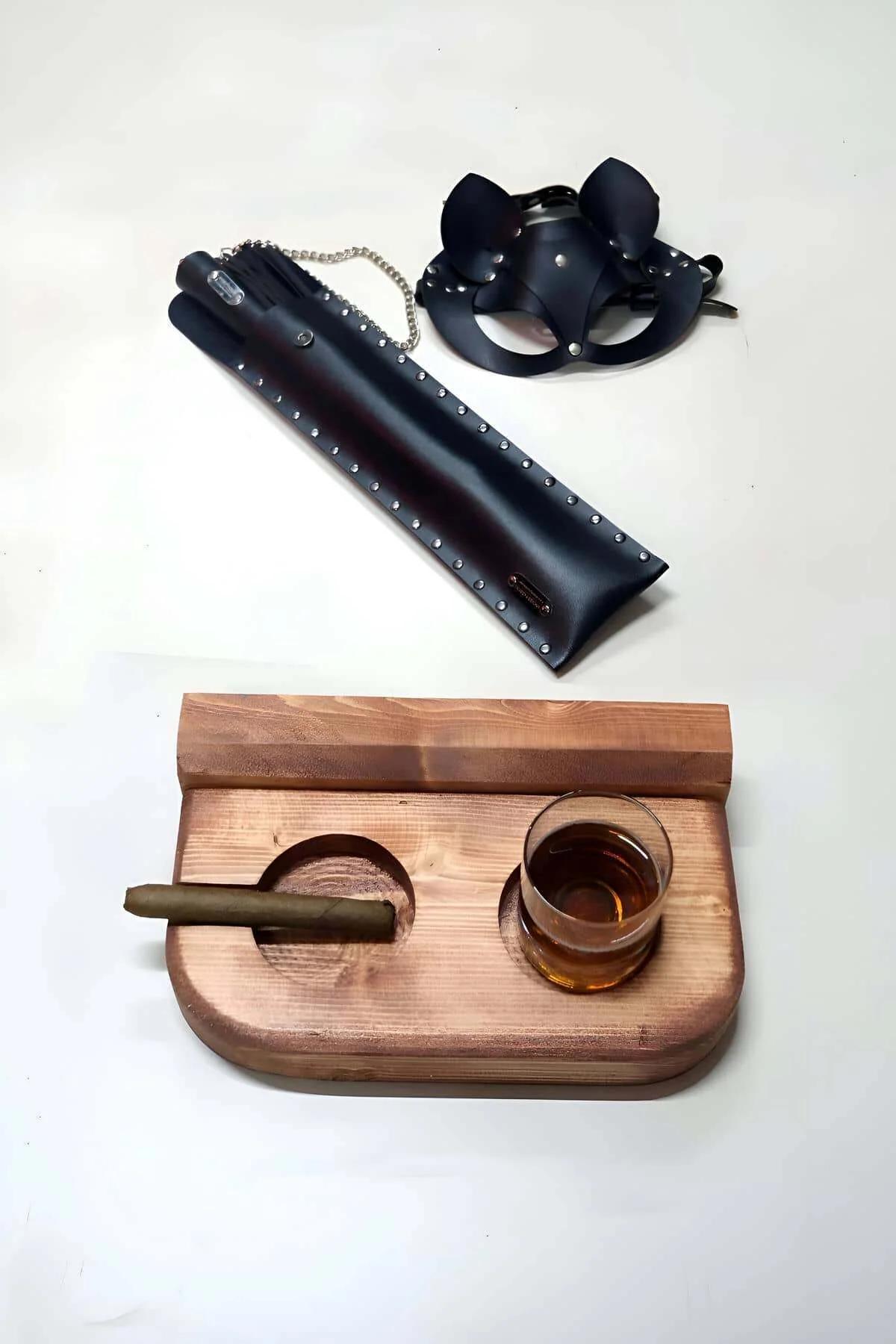 black faux leather cat ear mask and studded handle whip set with silver chain accent laid flat on white surface