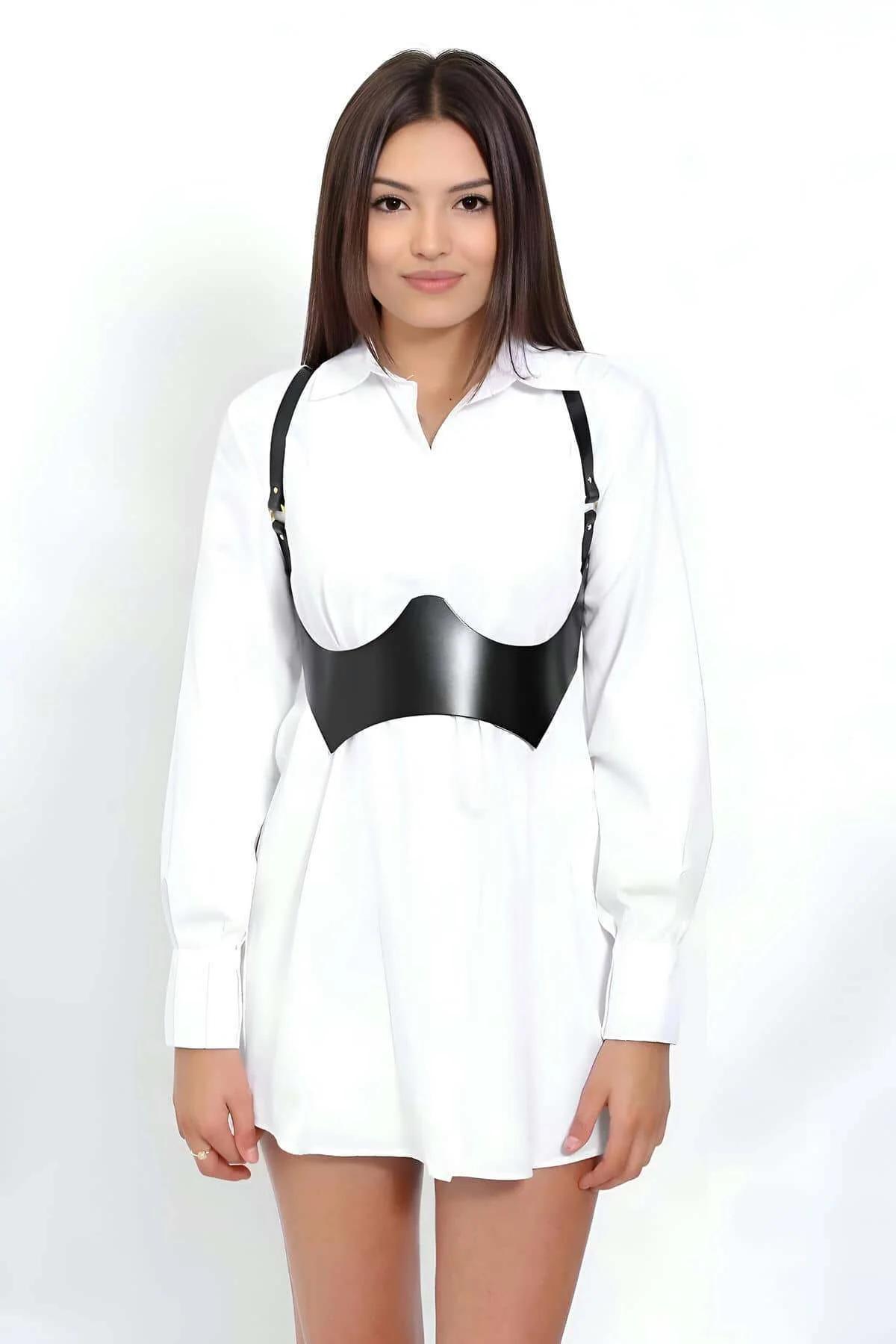 black faux leather contoured corset body harness with gold hardware shoulder straps worn over white shirt dress