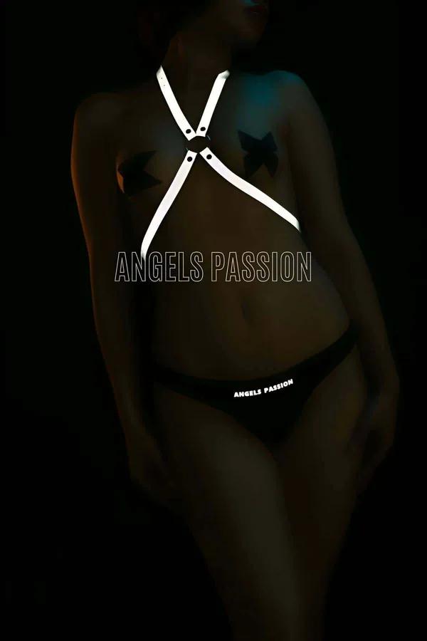 Reflective white cross body harness with silver O-ring closure glowing in low light on dark background