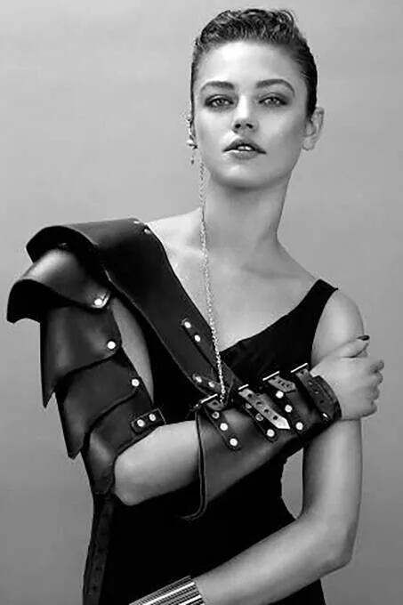 Black matte faux leather asymmetric shoulder and arm harness with silver dome studs and three buckle straps on forearm
