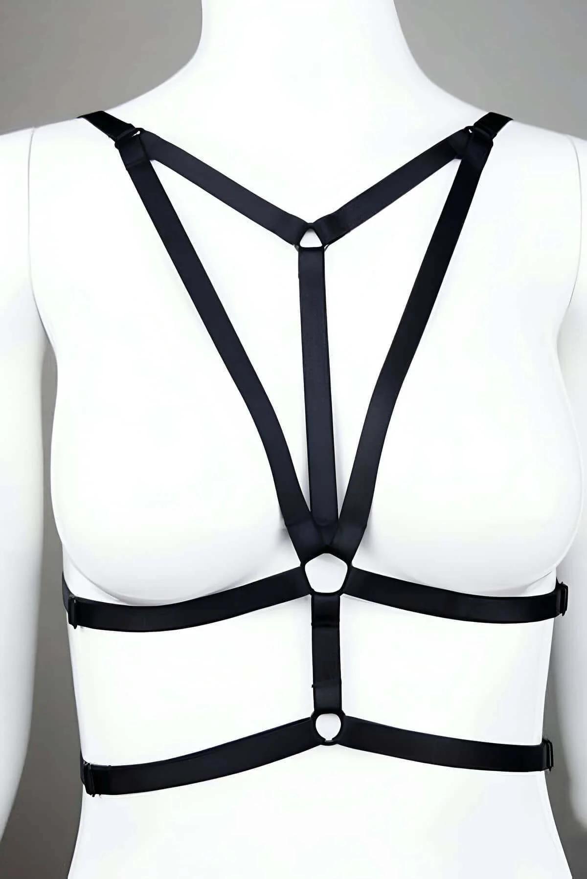 Black strappy chest harness with Y-strap silhouette and dual O-ring accents on white mannequin