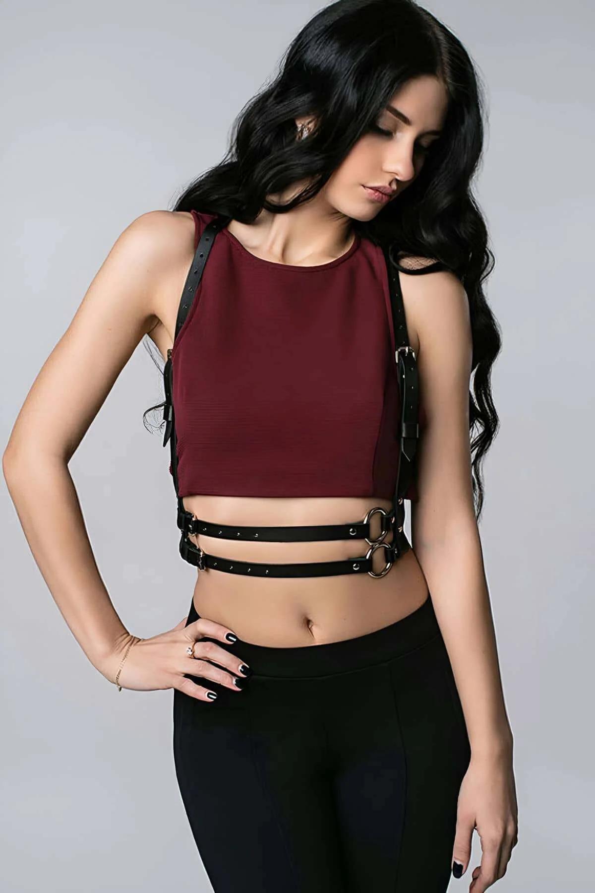 black faux leather chest harness with double antique gold O-rings and studded adjustable shoulder straps worn over burgundy c