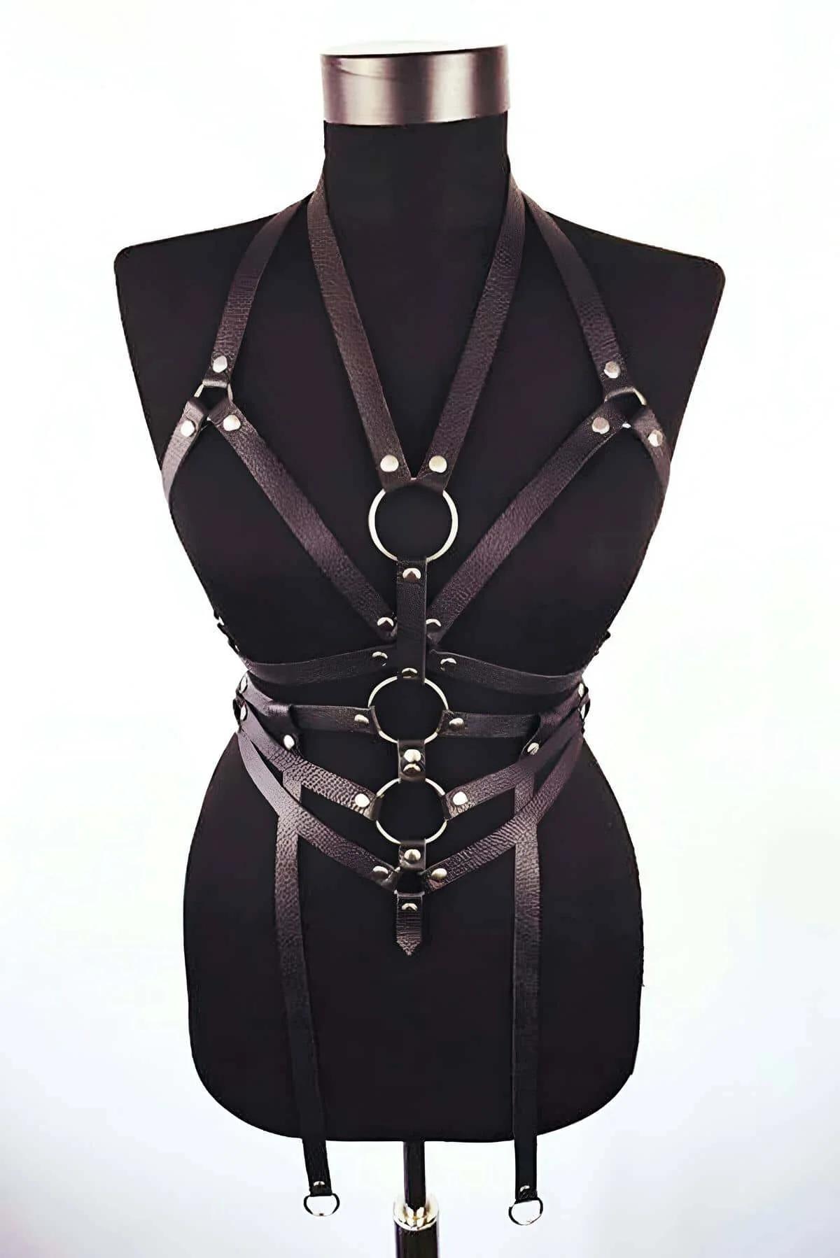 Black faux leather multi-strap body harness with three silver O-rings on dress form front view