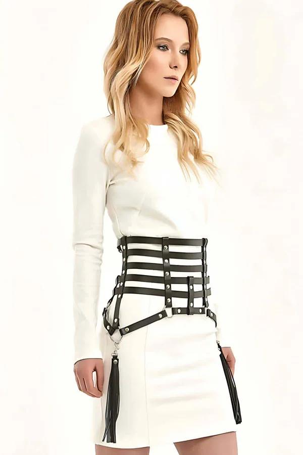 Black faux leather corset harness belt with five cage straps, silver studs, and two hanging tassels worn over white dress