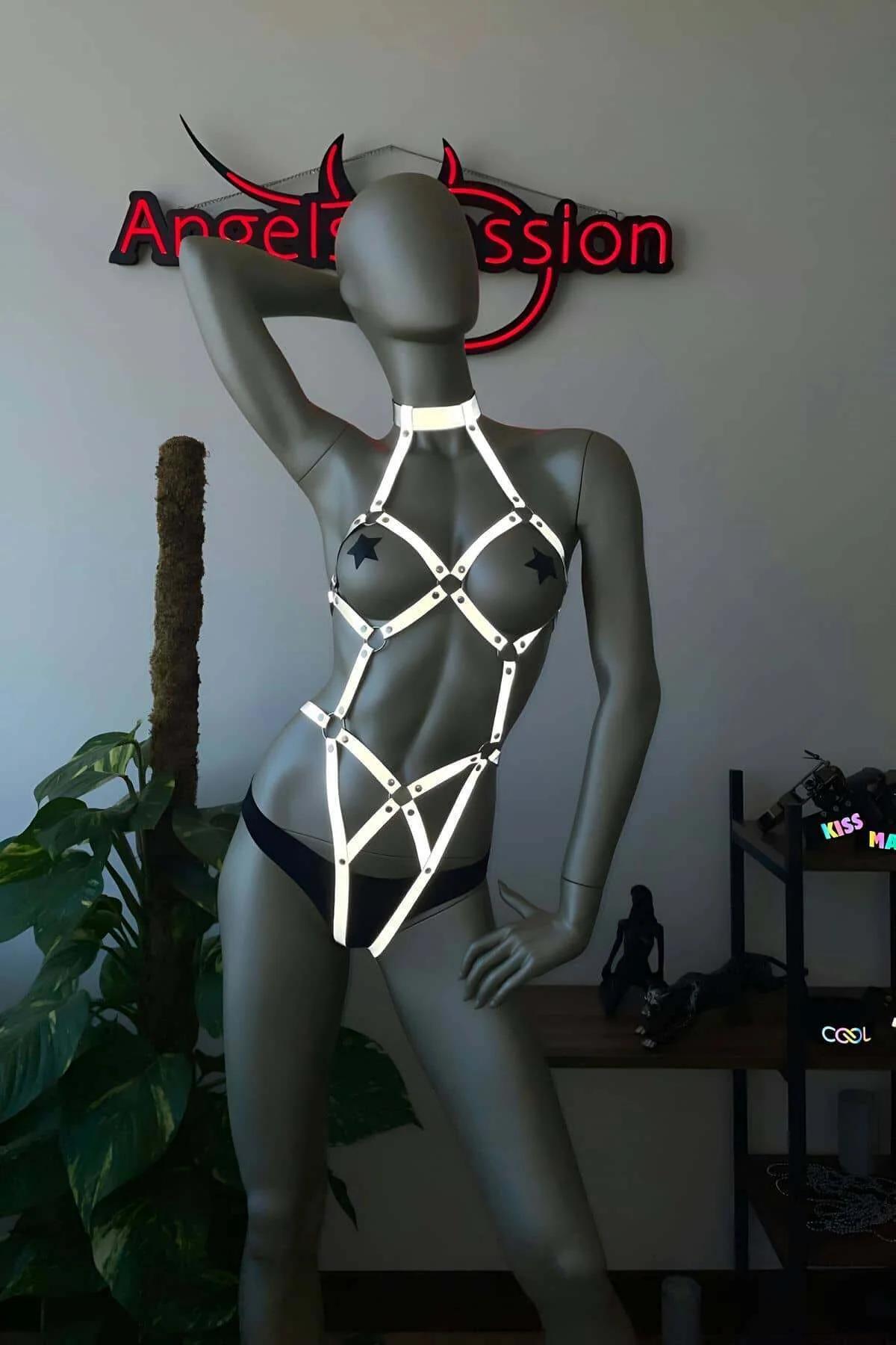 White reflective full body harness with star-shaped silver hardware on grey mannequin, geometric cage strap design from neck