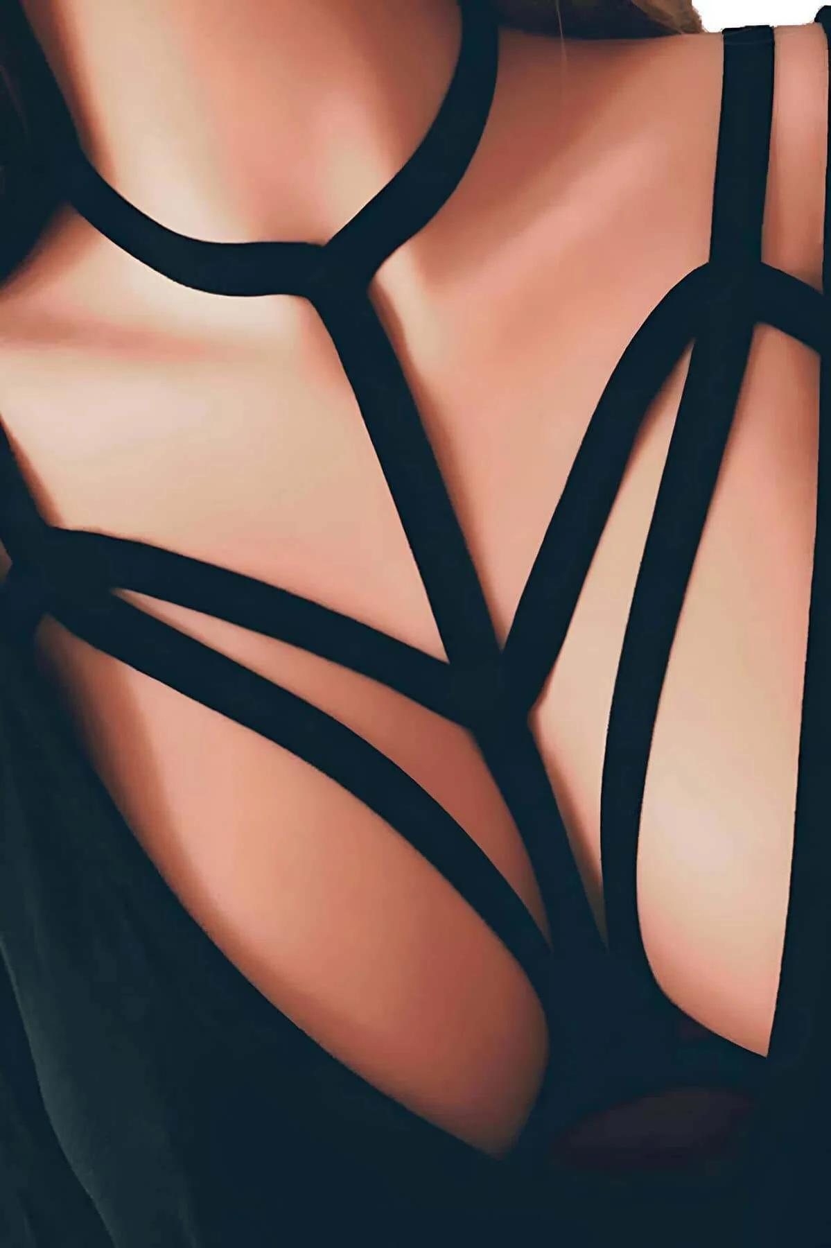 Black strappy caged body harness with wide flat elastic bands in geometric chest cage pattern on model