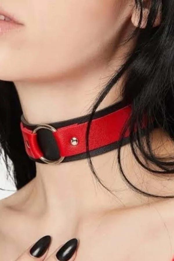 Red faux leather choker with black trim edges and silver O-ring worn around a model's neck showing pin-buckle closure detail