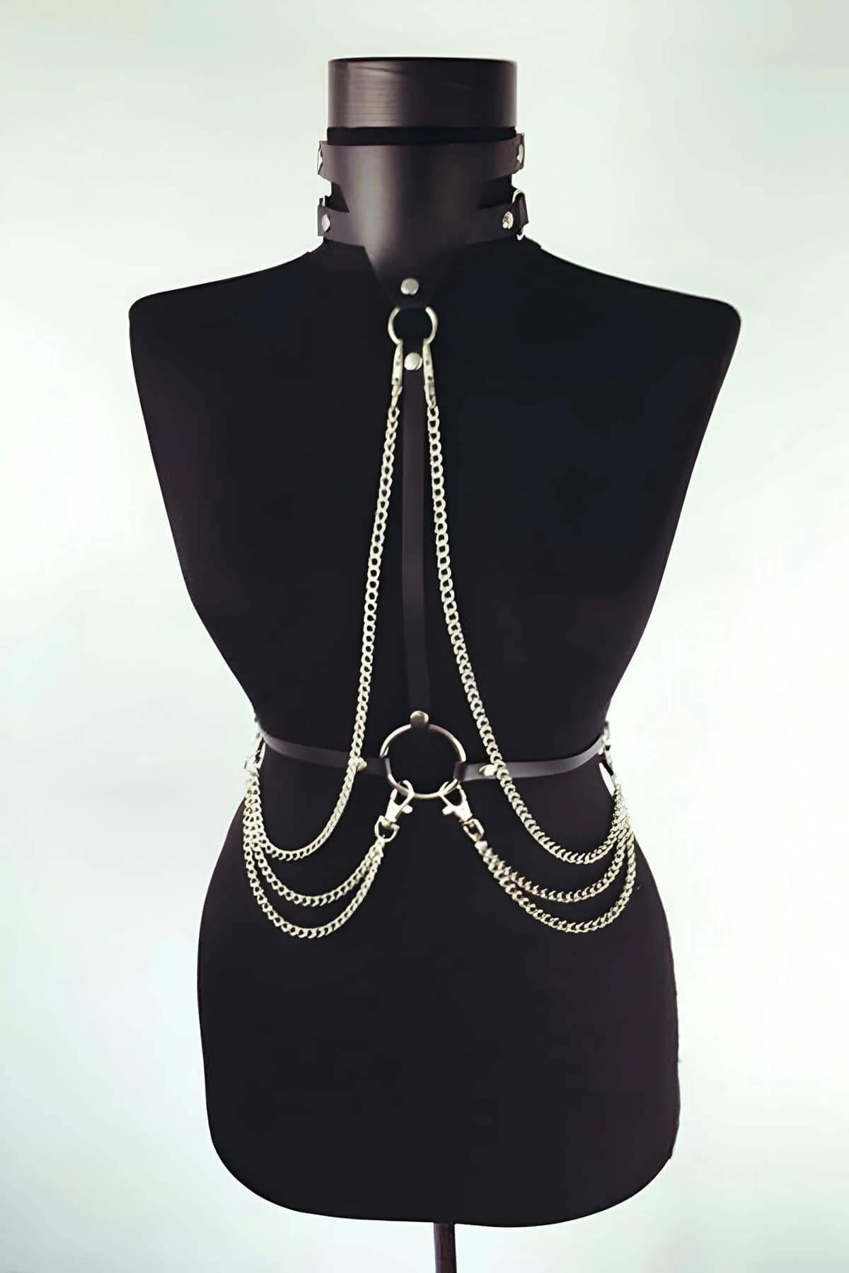 Black faux leather chest harness with three cascading silver curb-link chains and integrated choker on mannequin