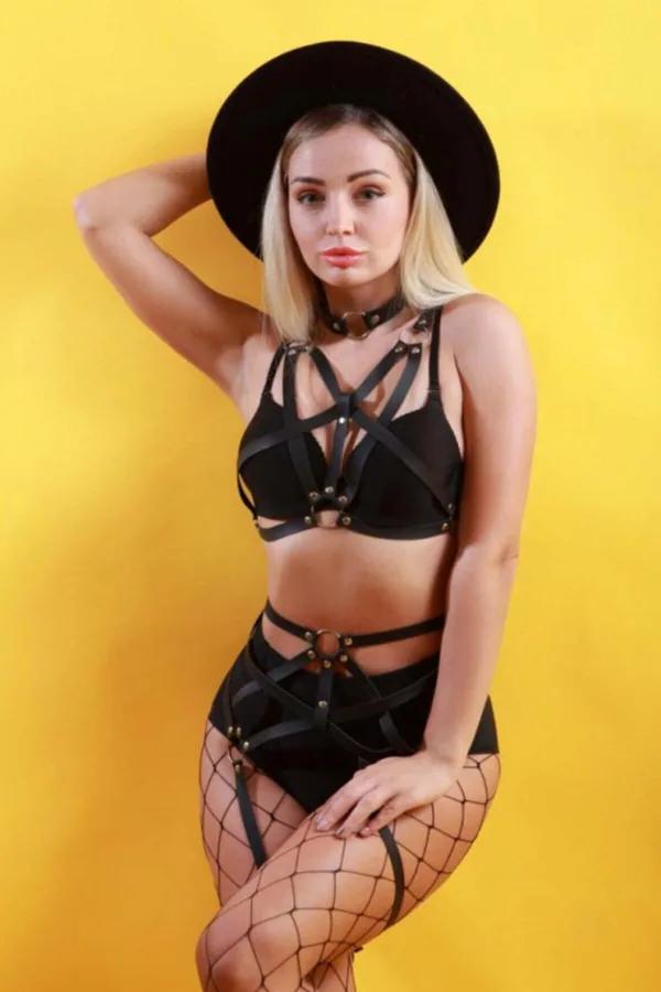Black strappy PU faux leather body harness and garter set with gold-tone O-rings and stud rivets, worn over black lingerie