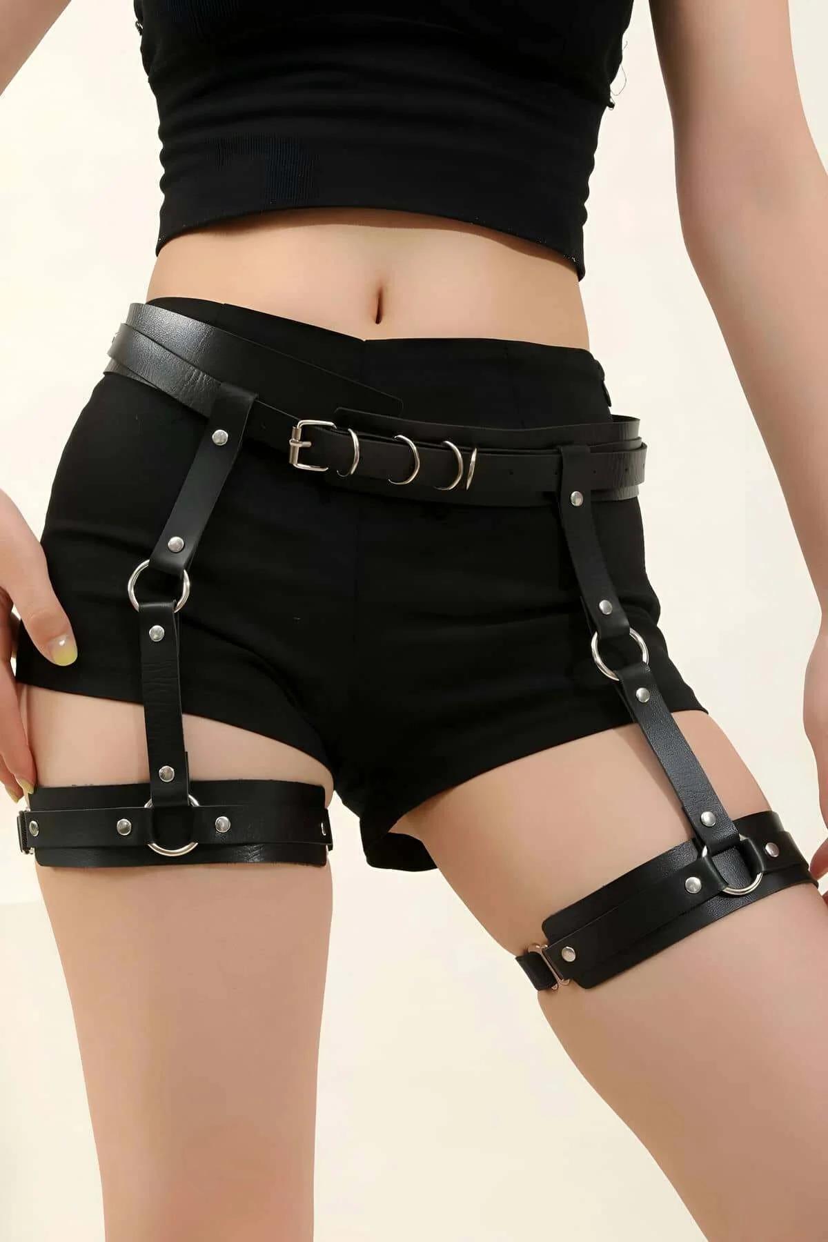 black faux leather garter harness belt with silver O-rings and pin buckle worn over black shorts
