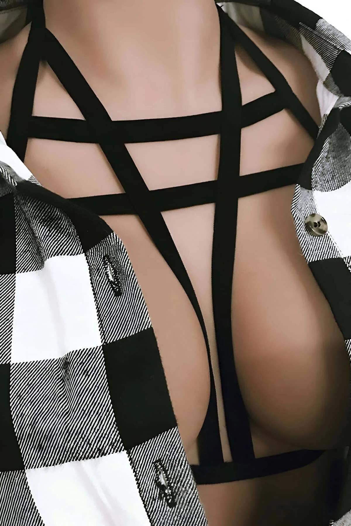 Black geometric chest harness with angular crossing elastic straps layered over plaid shirt, front view