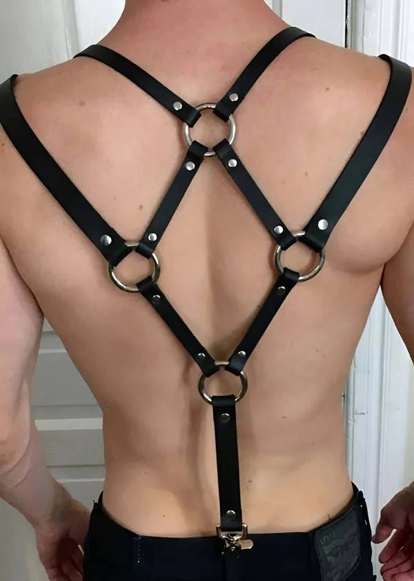 Black faux leather back harness with four silver O-rings and rivet hardware on male torso, rear view