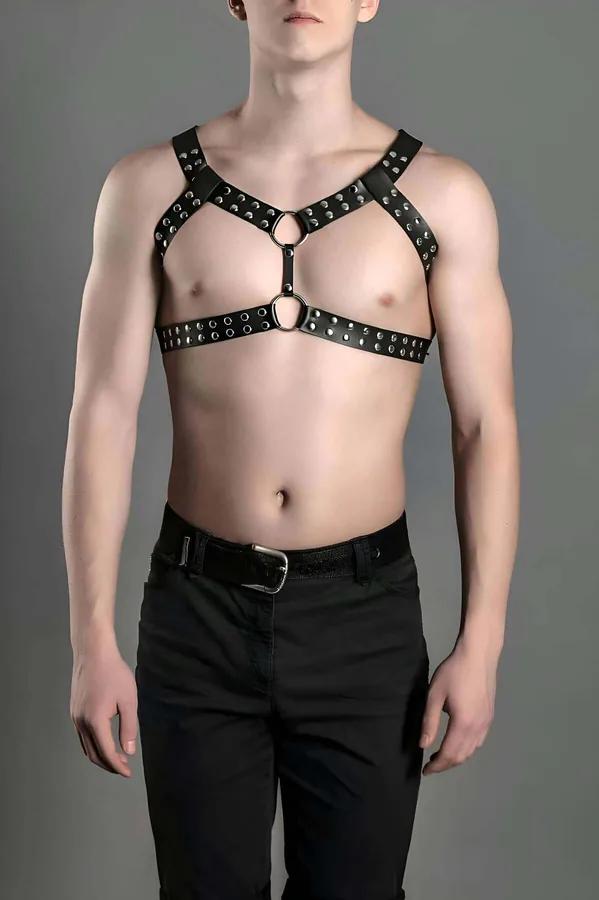 black faux leather chest harness with dual silver O-rings and dome studs in X-strap configuration on male model
