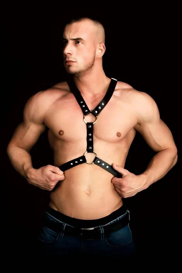Black faux leather men's chest harness with two silver O-rings and dome studs, Y-strap design worn by male model