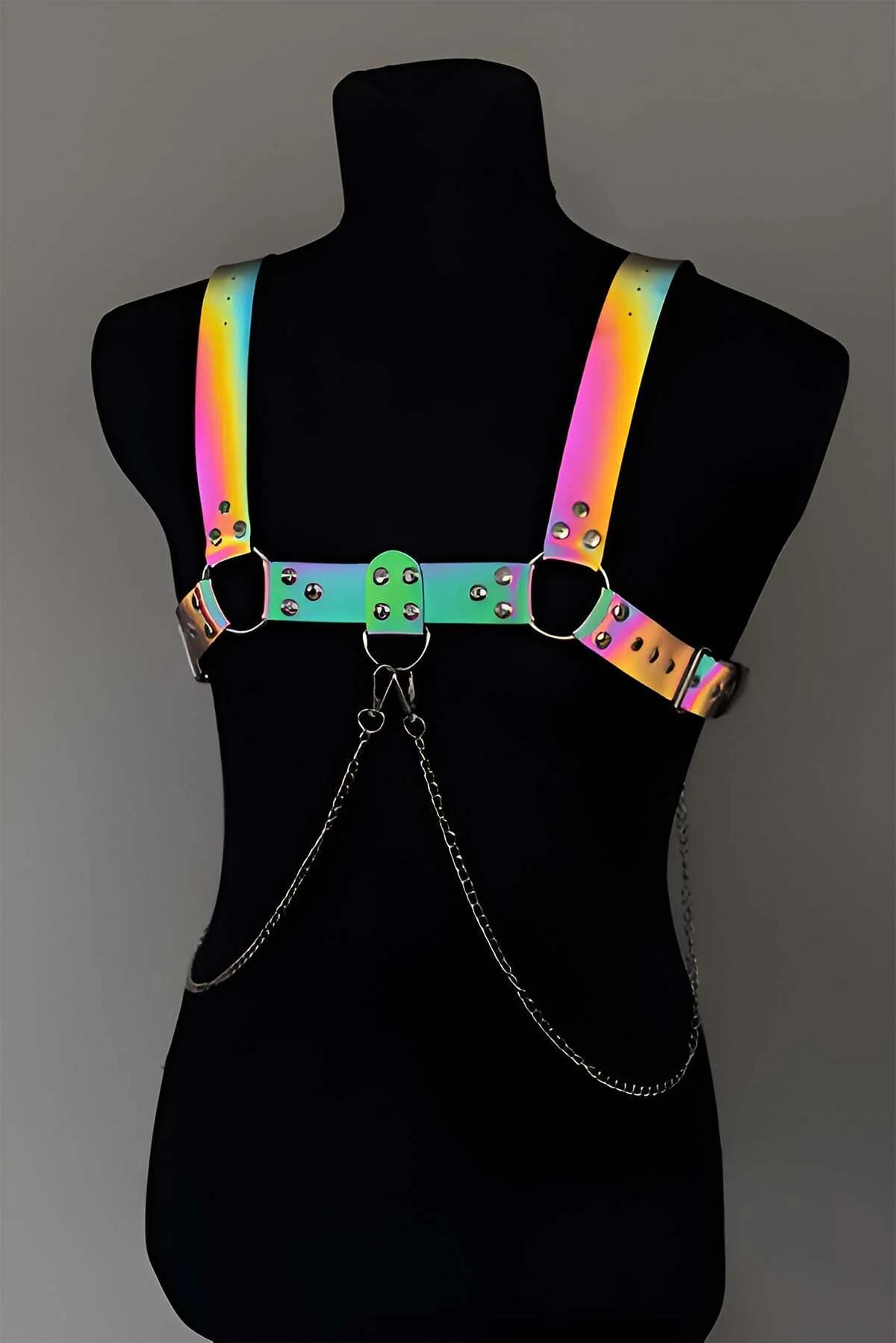 Rainbow iridescent chest harness with wide holographic PU straps, silver O-rings, rivet studs, and draped double-loop silver
