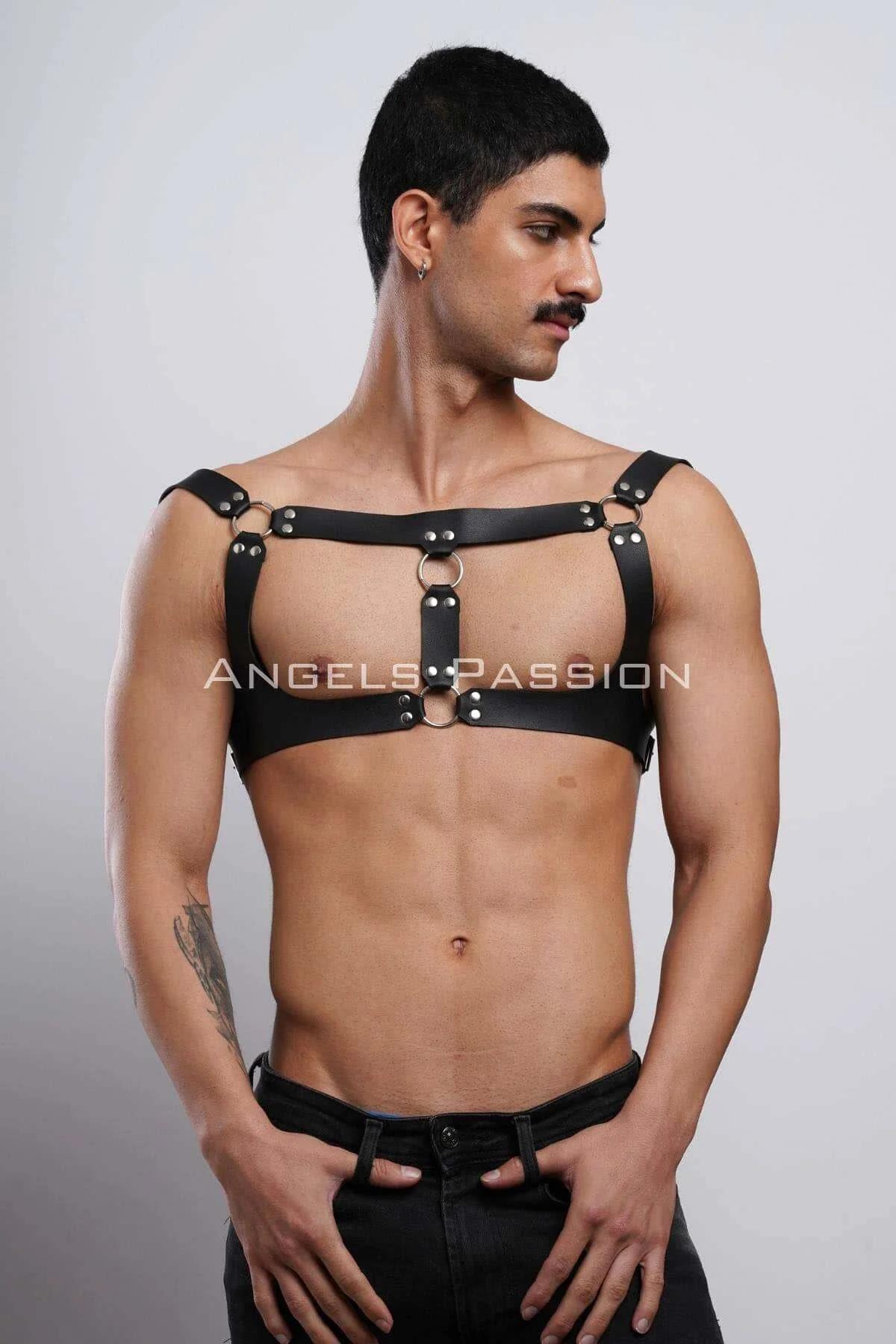 Black faux leather chest harness with dual stacked silver O-rings and rivets, worn by male model, adjustable shoulder straps