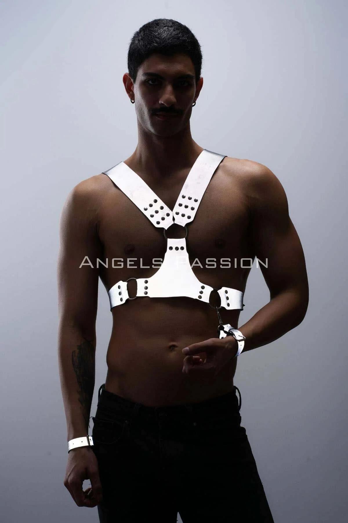White reflective faux leather chest harness with black stud clusters and O-ring, matching wrist cuffs, worn by male model