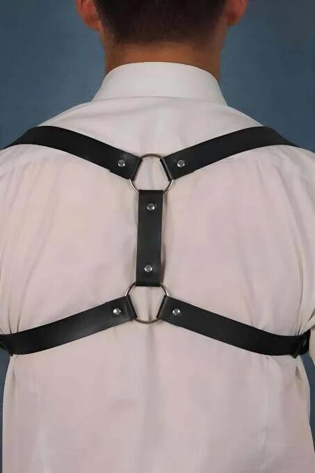 black faux leather back-strap harness with dual silver O-rings and X-strap construction worn over white shirt