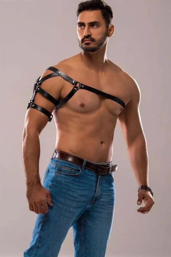 black faux leather asymmetrical shoulder harness with dual arm bands and silver buckles worn by male model