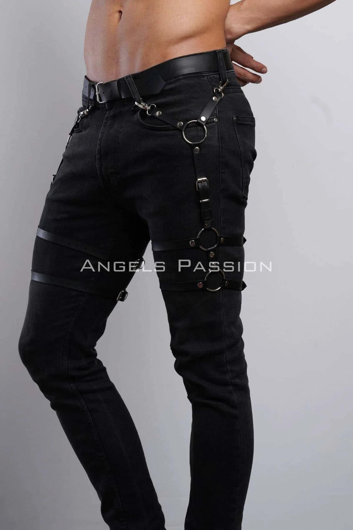black faux leather leg harness with three silver O-rings worn over black jeans, adjustable buckle straps at hip thigh and kne