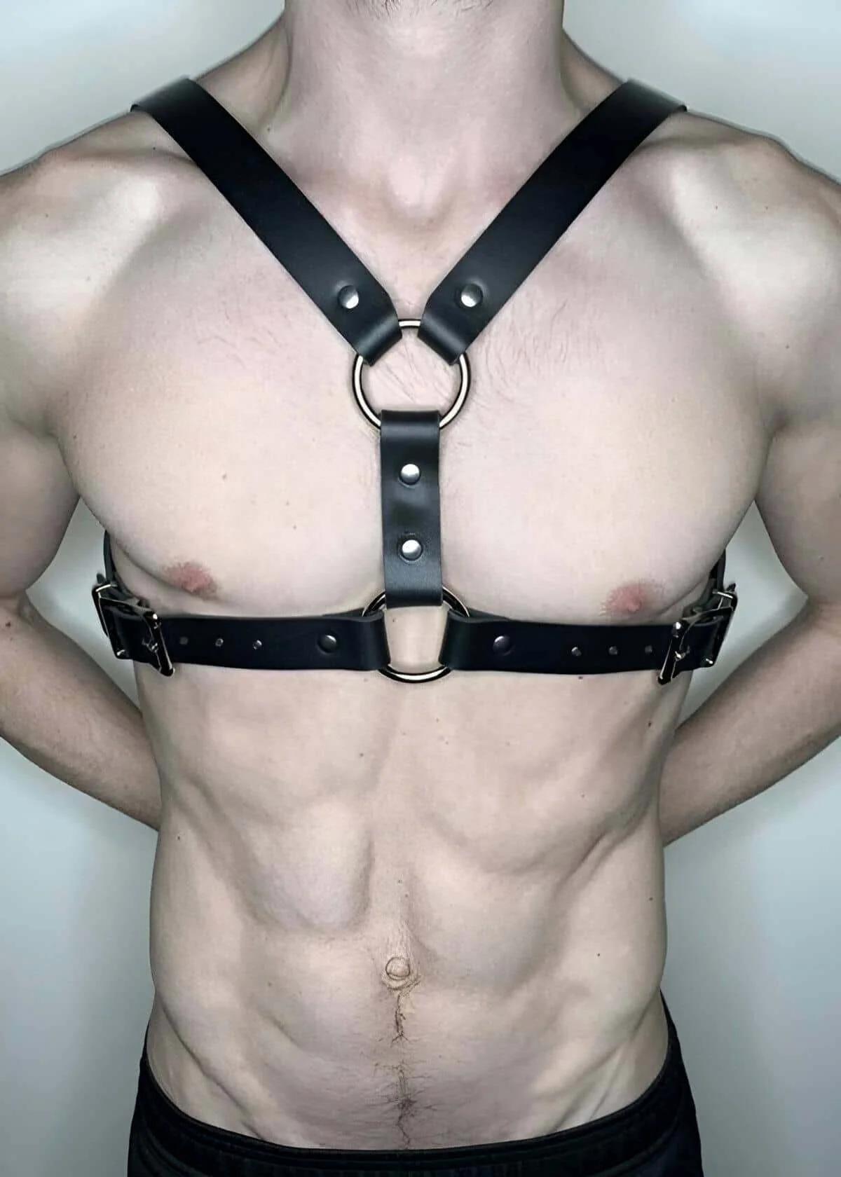 black faux leather chest harness with double silver O-rings and adjustable buckle straps worn on male torso