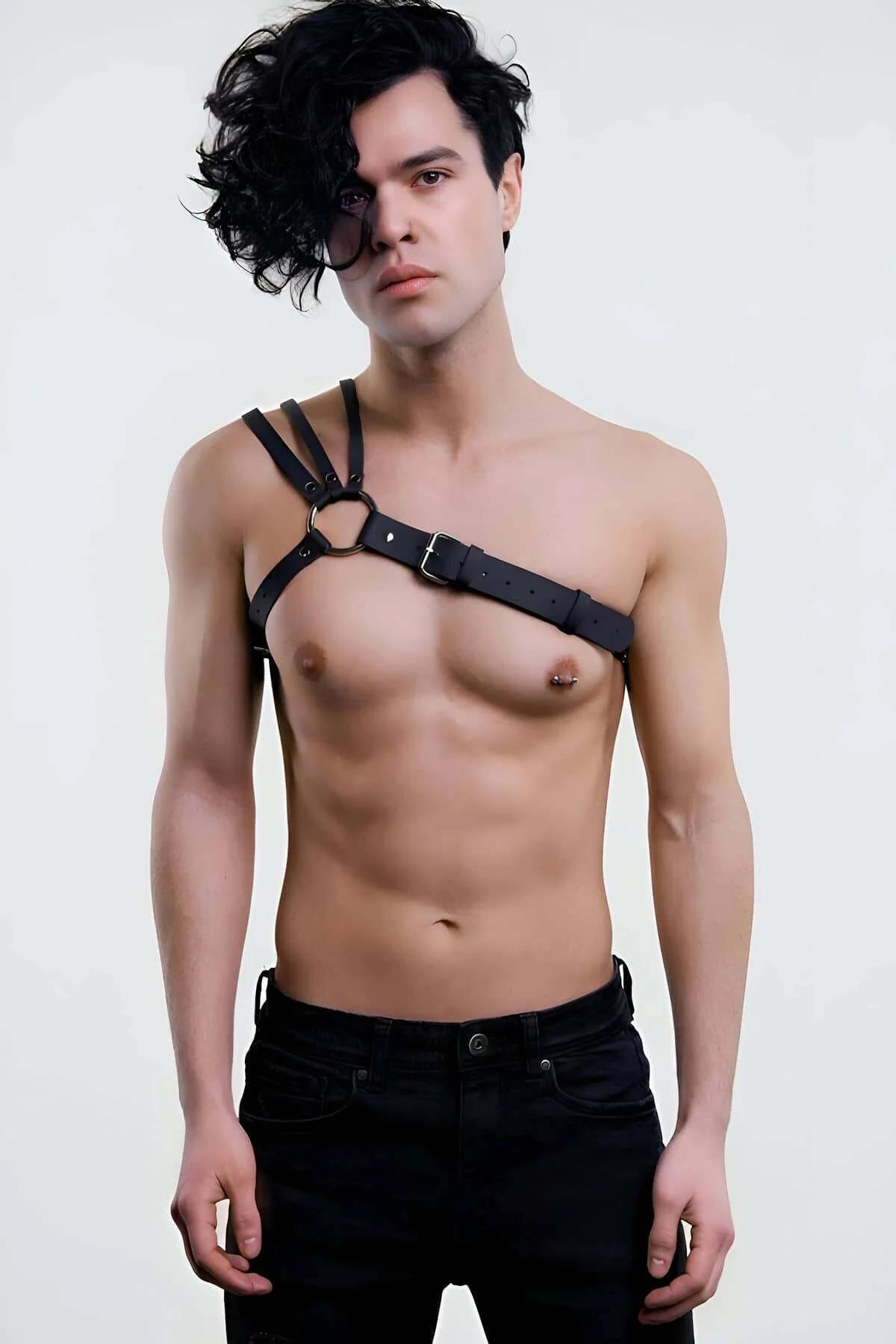 Black faux leather asymmetrical chest harness strap with silver O-ring on male model, single-shoulder design