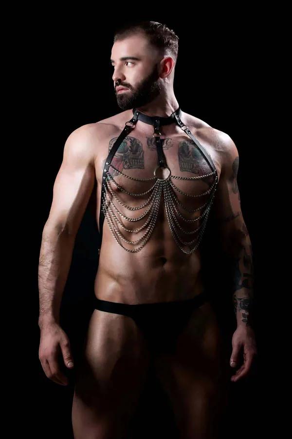 Black faux leather chest harness with cascading silver chains and central O-ring worn by male model