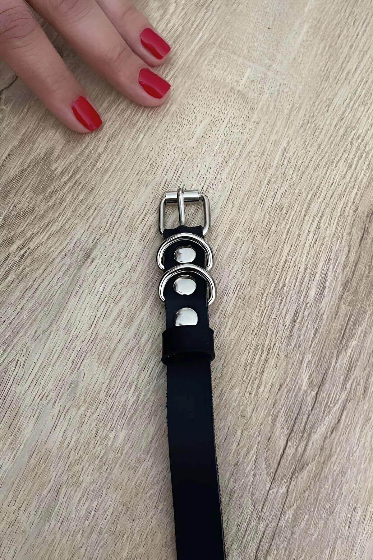 Black vegan leather strap with dual silver D-rings and pin buckle on wooden surface